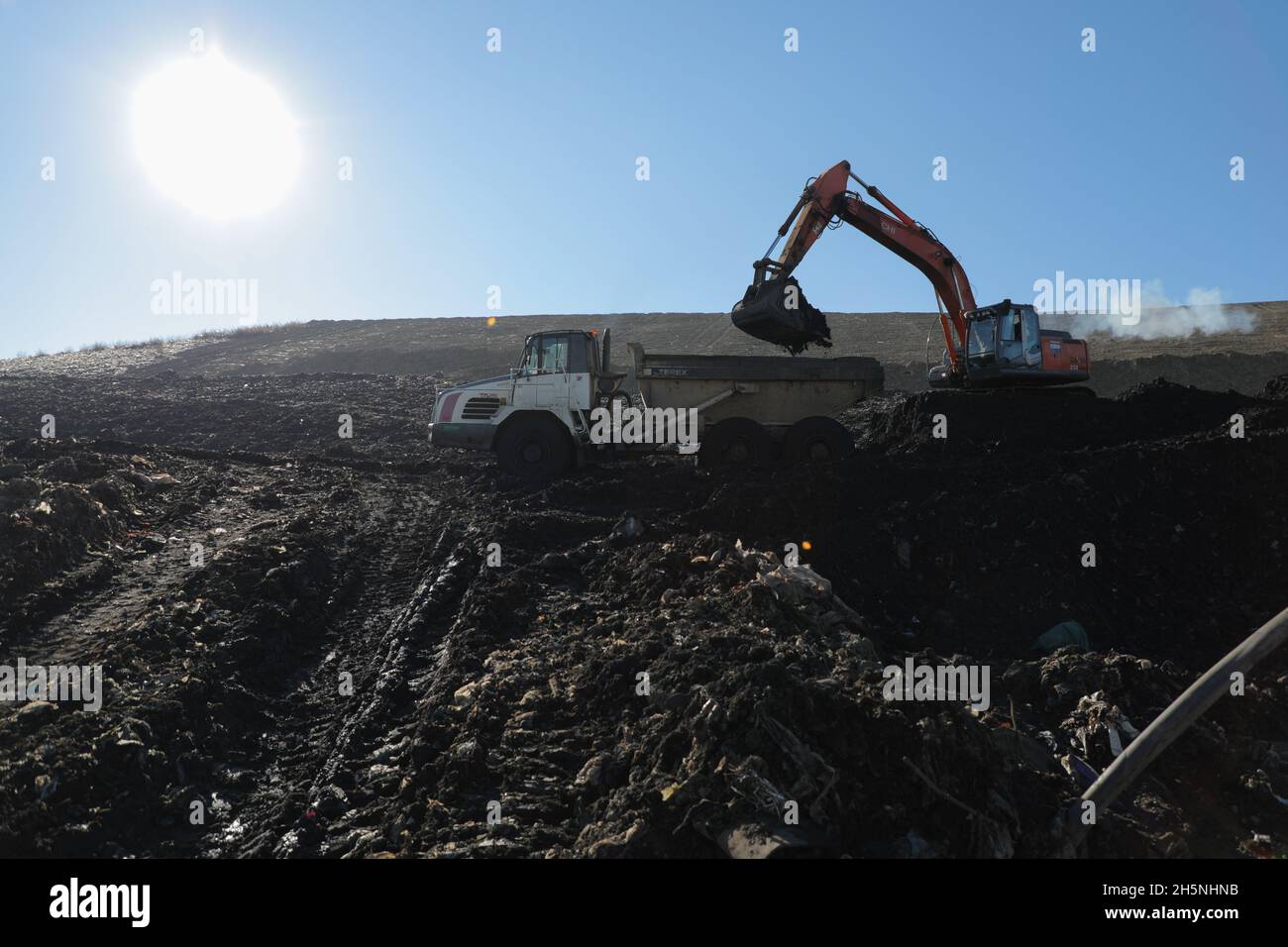 An excavator seen at the Hrybovytchi landfill which is under reclamation (artificial restoration of soil fertility and vegetation after man-made disturbance of nature). The only legal place for garbage collection from Lviv and surrounding villages. It has been operating since 1958 close to the village of Velyki Hrybovychi. The landfill area is over 38 hectares. On May 28, 2016, a large fire broke out on the territory of the Hrybovytsia landfill causing a collapse of solid waste where three rescuers died under the rubble. Stock Photo