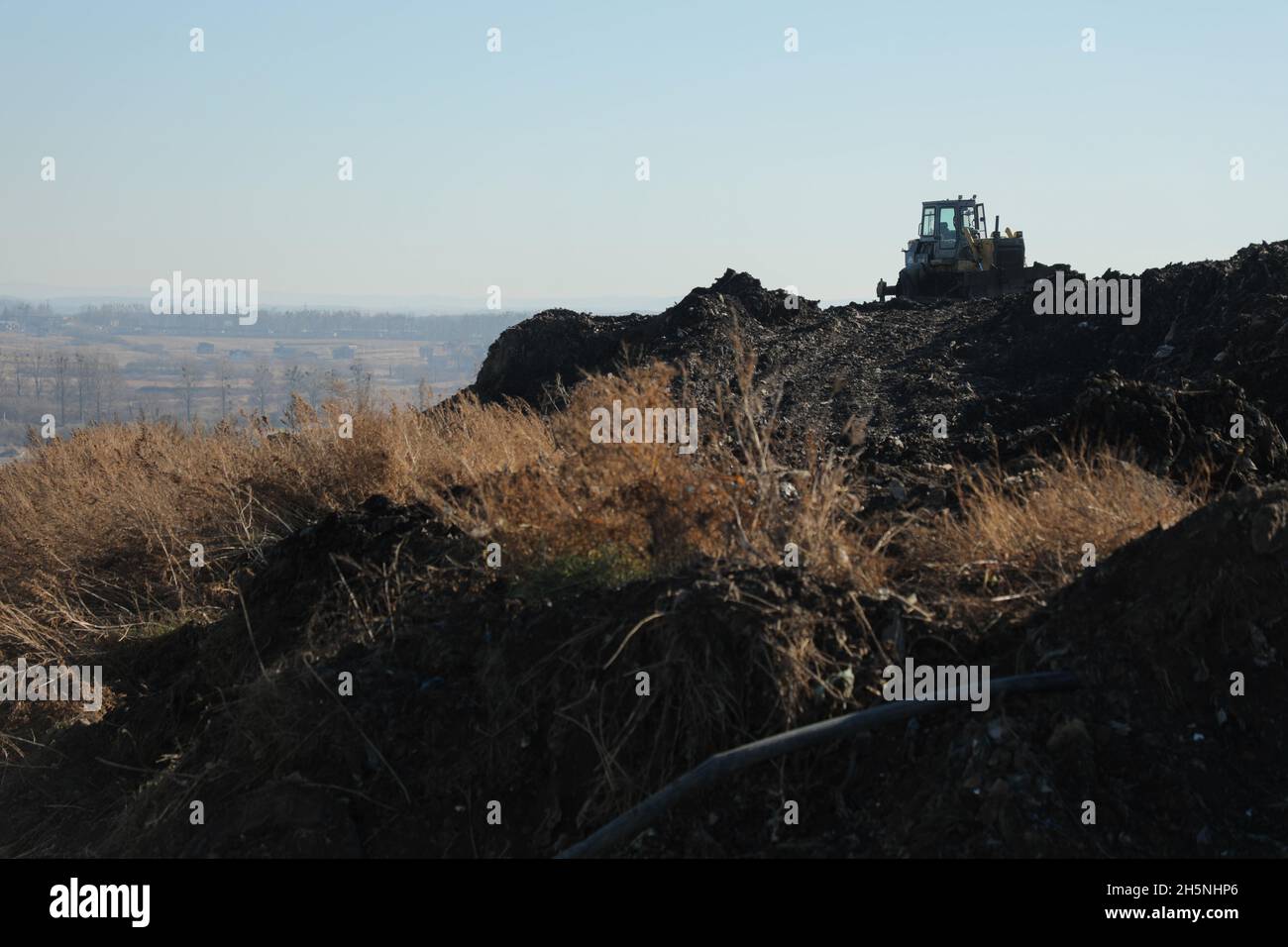 An excavator seen at the Hrybovytchi landfill which is under reclamation (artificial restoration of soil fertility and vegetation after man-made disturbance of nature). The only legal place for garbage collection from Lviv and surrounding villages. It has been operating since 1958 close to the village of Velyki Hrybovychi. The landfill area is over 38 hectares. On May 28, 2016, a large fire broke out on the territory of the Hrybovytsia landfill causing a collapse of solid waste where three rescuers died under the rubble. Stock Photo