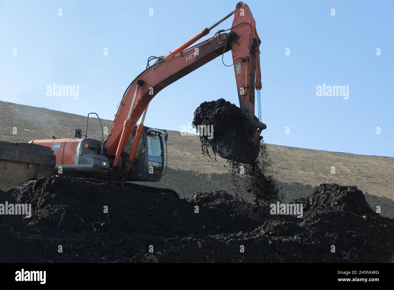 An excavator seen at the Hrybovytchi landfill which is under reclamation (artificial restoration of soil fertility and vegetation after man-made disturbance of nature). The only legal place for garbage collection from Lviv and surrounding villages. It has been operating since 1958 close to the village of Velyki Hrybovychi. The landfill area is over 38 hectares. On May 28, 2016, a large fire broke out on the territory of the Hrybovytsia landfill causing a collapse of solid waste where three rescuers died under the rubble. Stock Photo