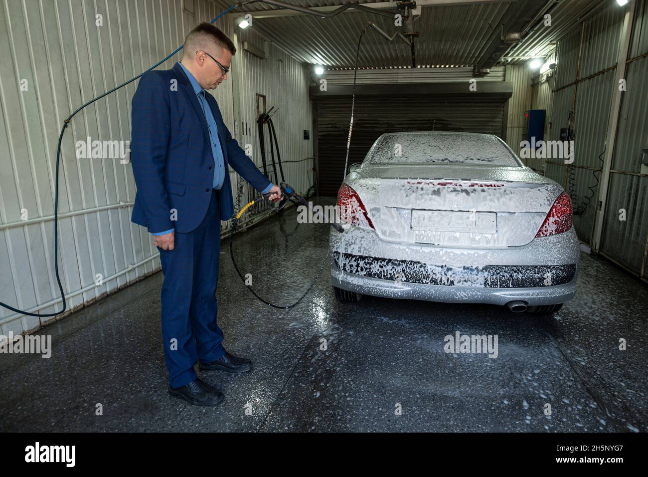 a man washes a car in a box contactless car wash selfservice with a
