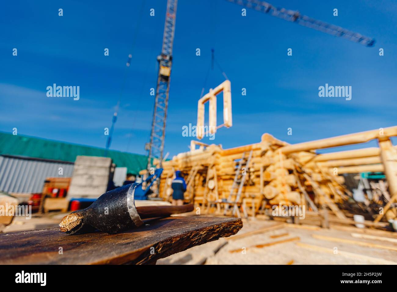Chisel for processing wood against background of construction site houses made of logs. Stock Photo