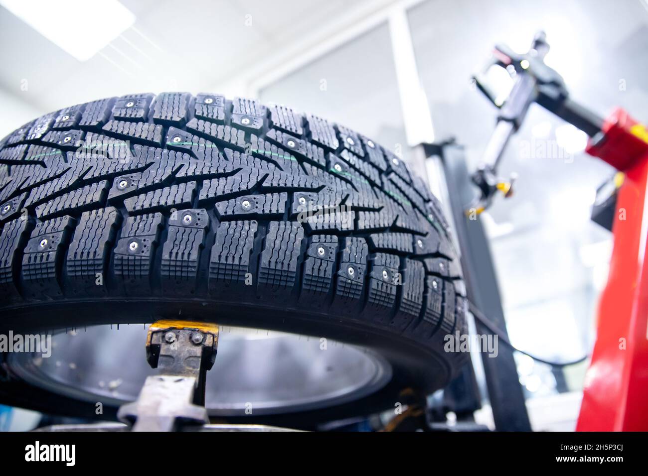 Close-up winter car tire with steel studs in service on machine tool. Stock Photo