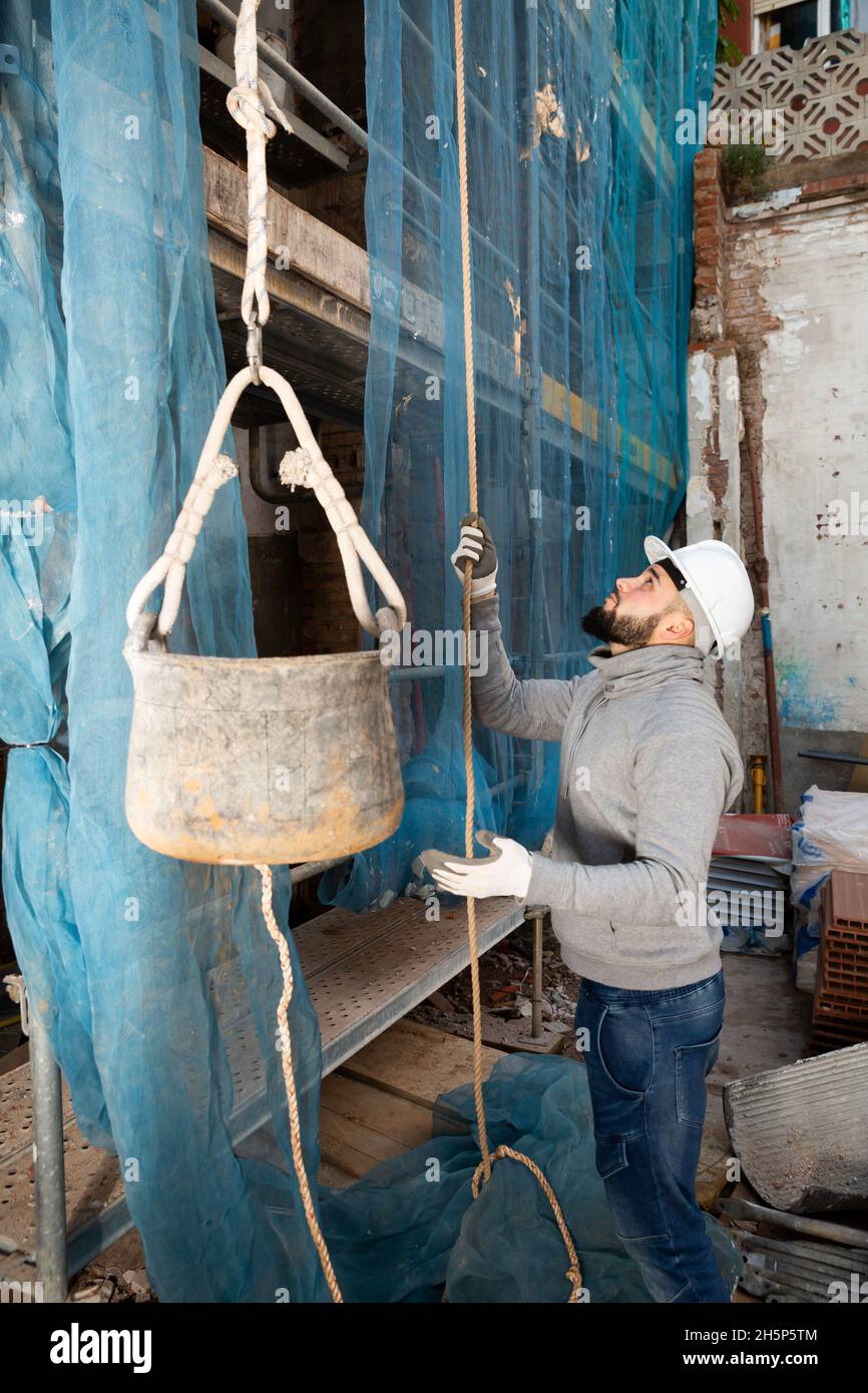 Worker lifting bucket with cement mortar Stock Photo Alamy