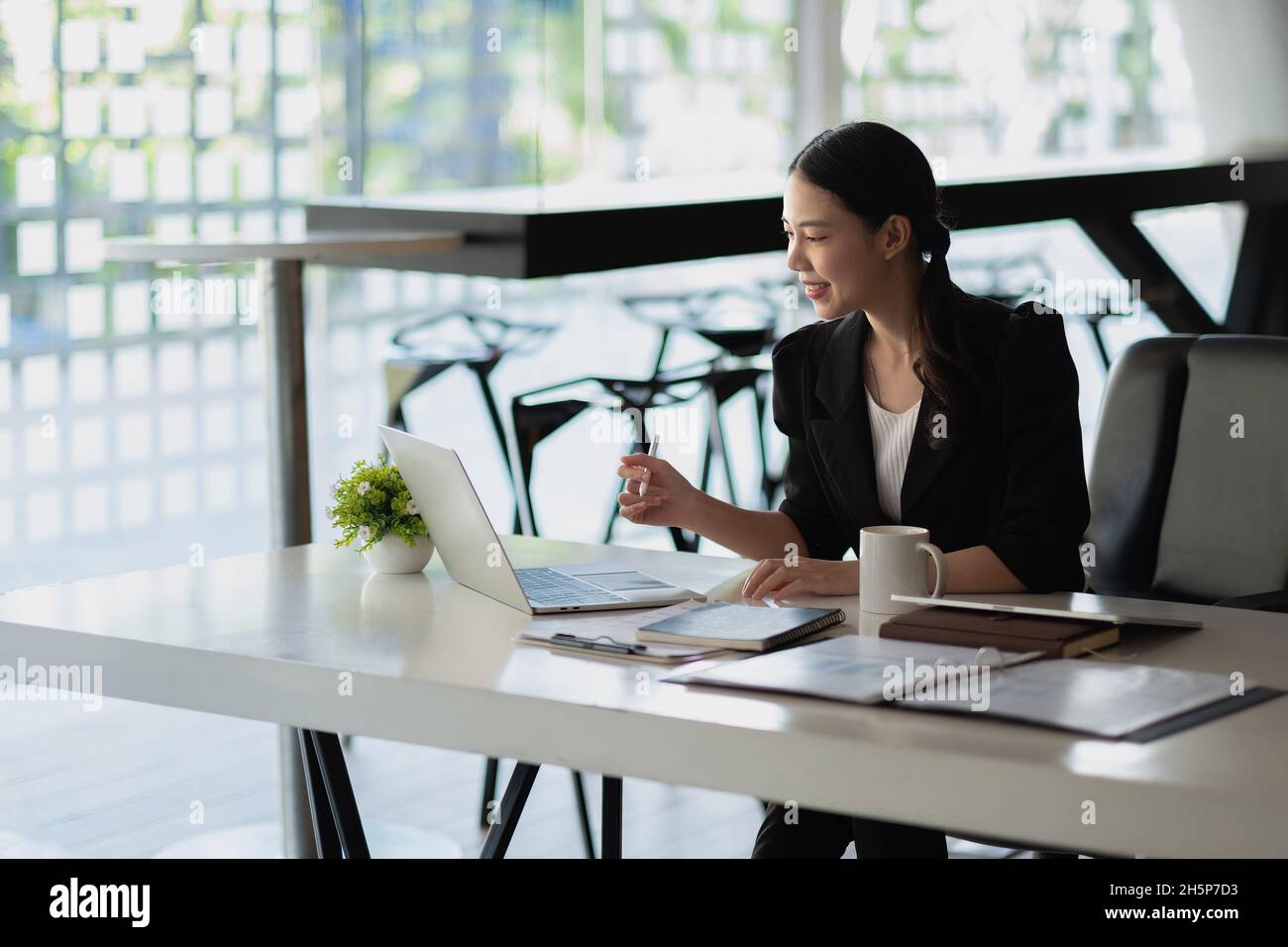 Charming asian businesswoman sitting working on laptop in office. Side ...