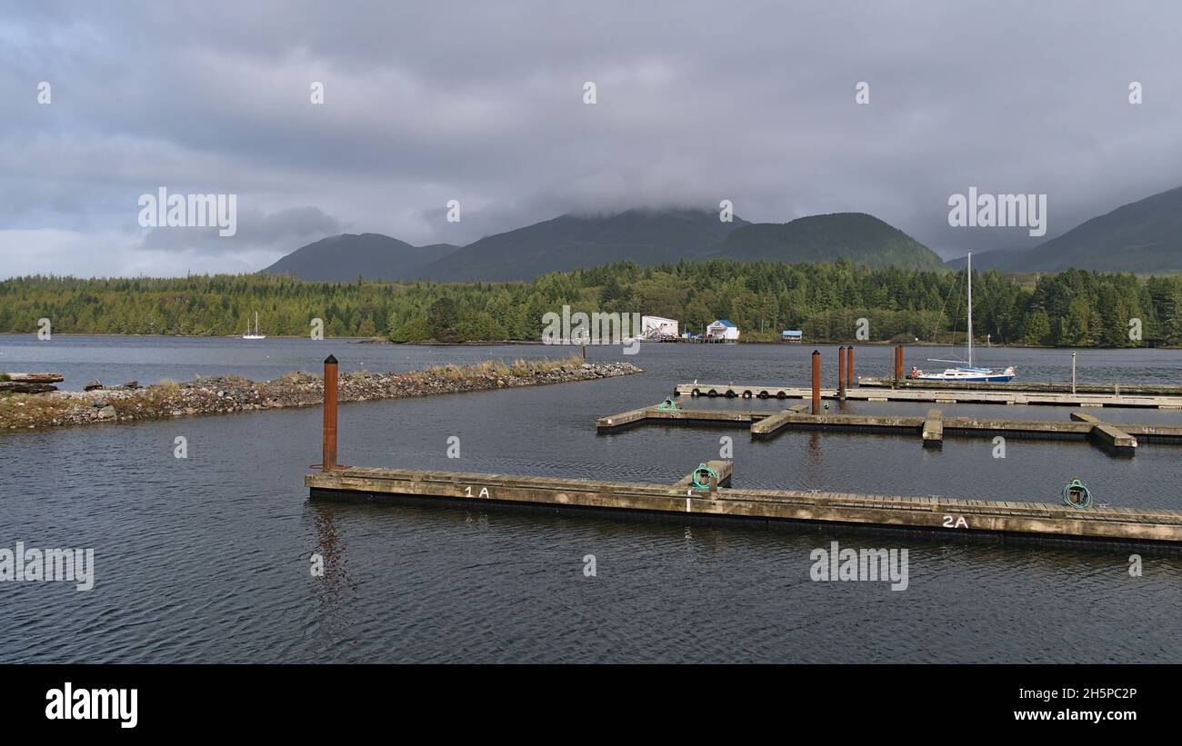 View of mostly empty jetty in the harbour of village Ucluelet on Vancouver Island, British Columbia, Canada on cloudy day in autumn with sailing boat. Stock Photo