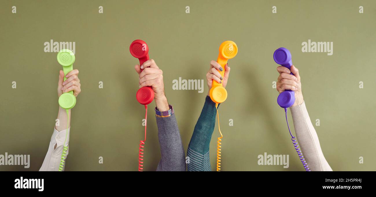 Banner with human hands holding landline phone receivers against green background Stock Photo
