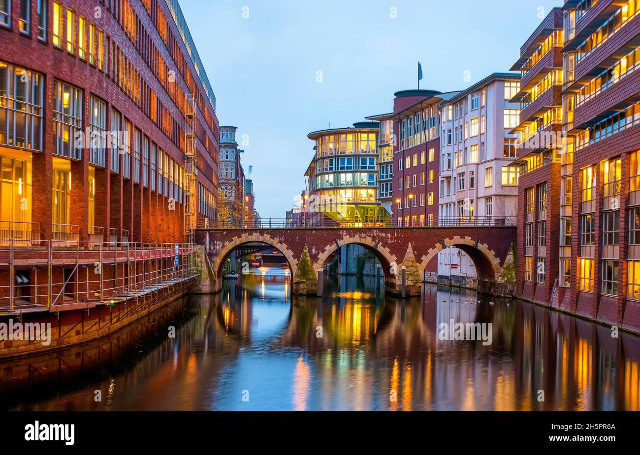 The stone Ellerntorsbrucke bridge over Herrengrabenfleet canal sandwiched between modern buildings of different purposes, Hamburg, Germany Stock Photo