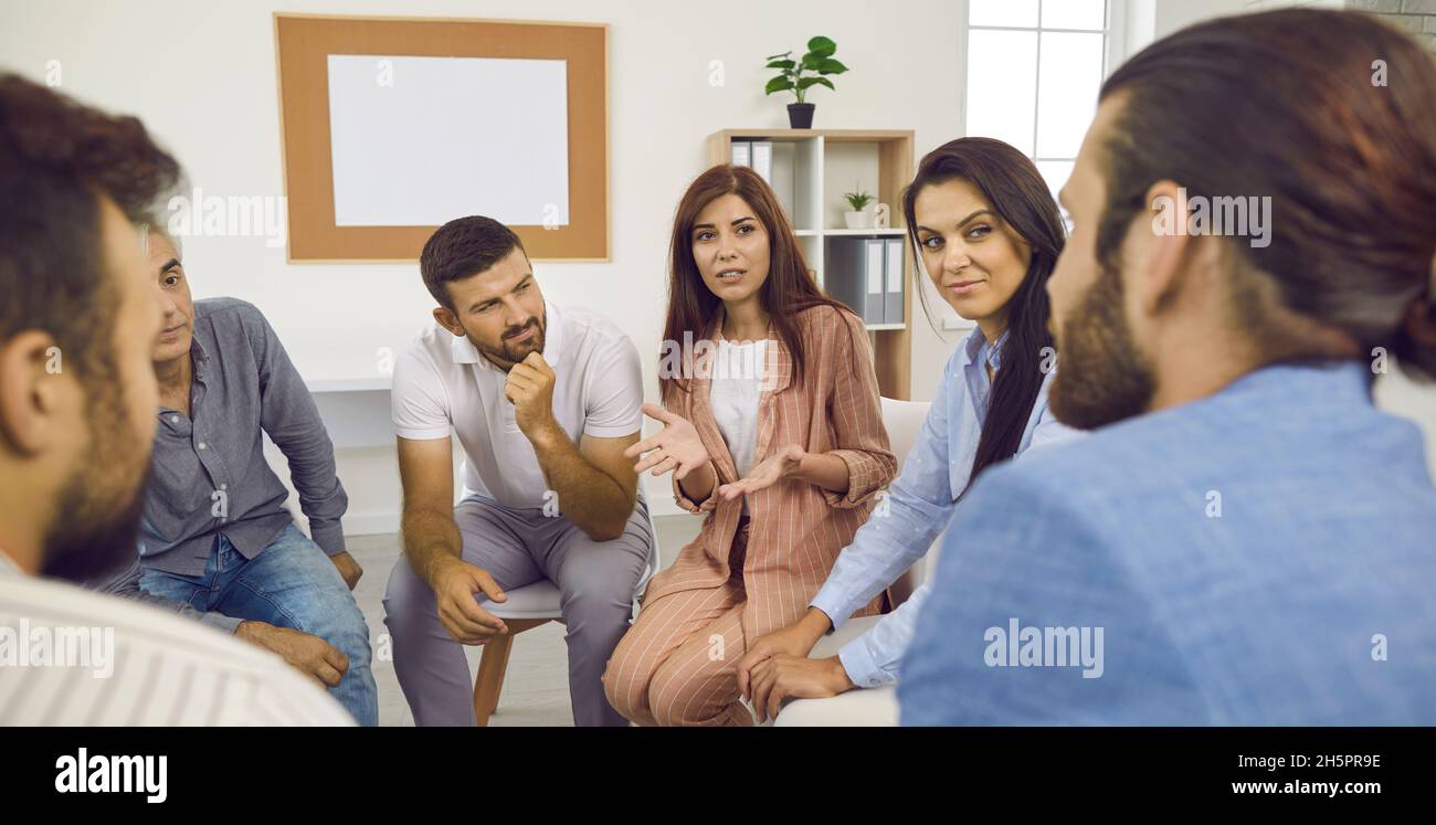 Female psychologist helps people get rid of their addictions during group therapy. Stock Photo