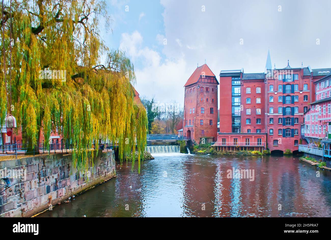 The view on Ilmenau River flowing in Luneburg old town and medieval tower on its bank, Germany Stock Photo