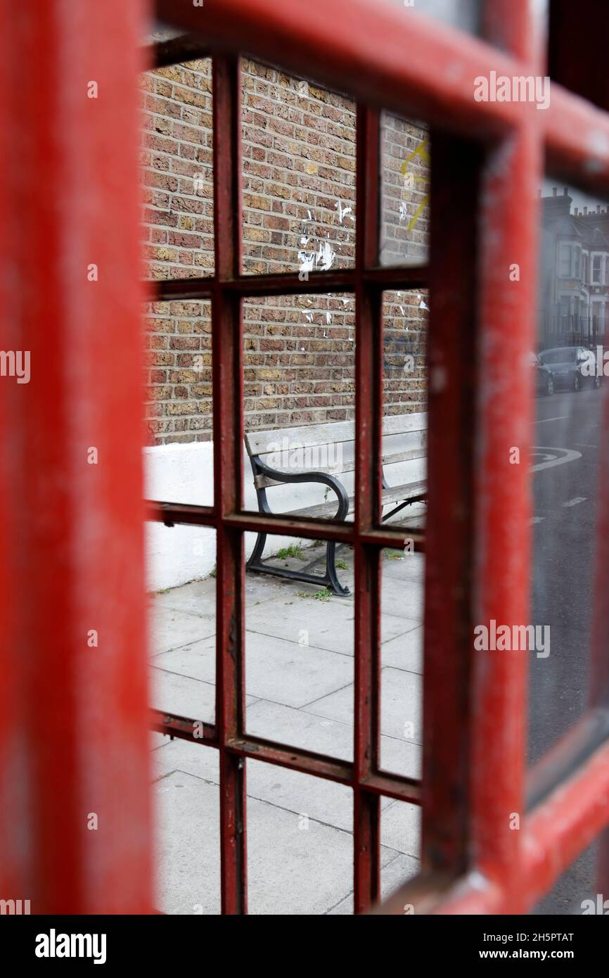 Bench seen through a telephone box on Waller Road, New Cross, London, UK Stock Photo