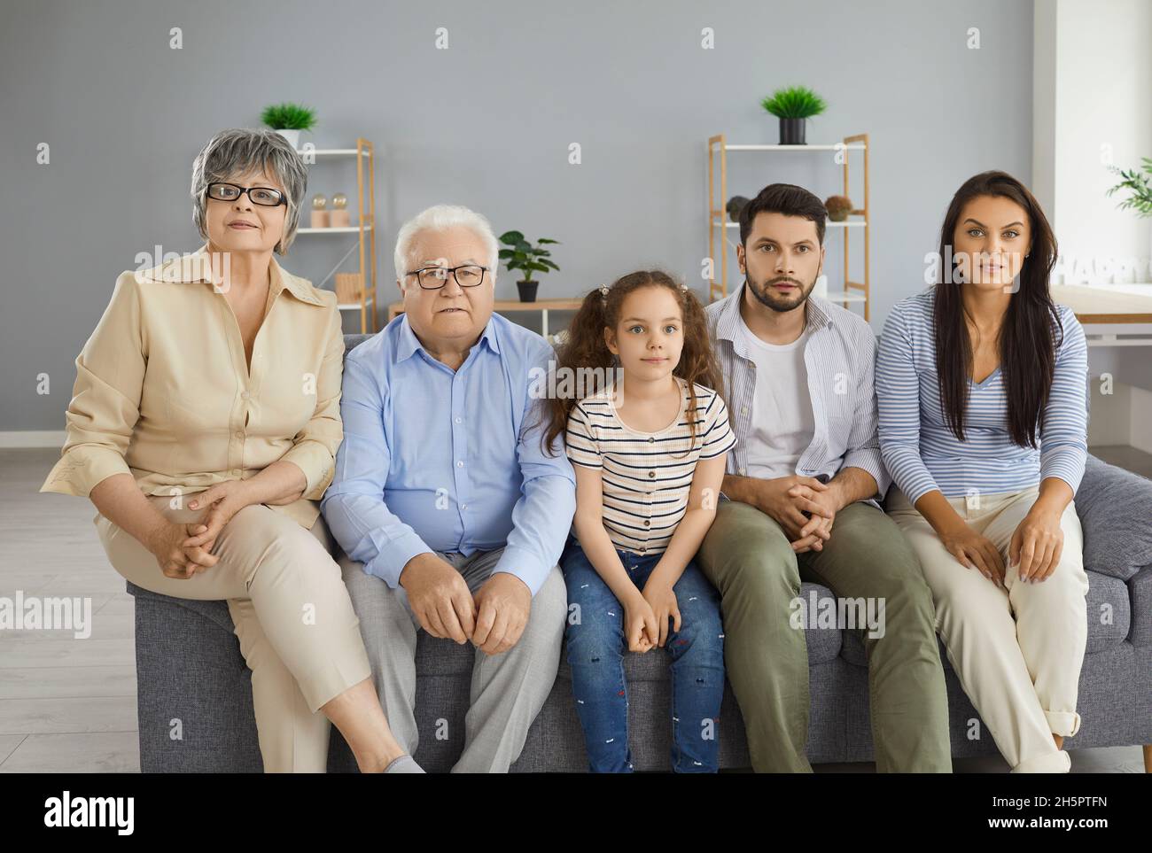 Multi generational family sitting on sofa at home and watching television together Stock Photo