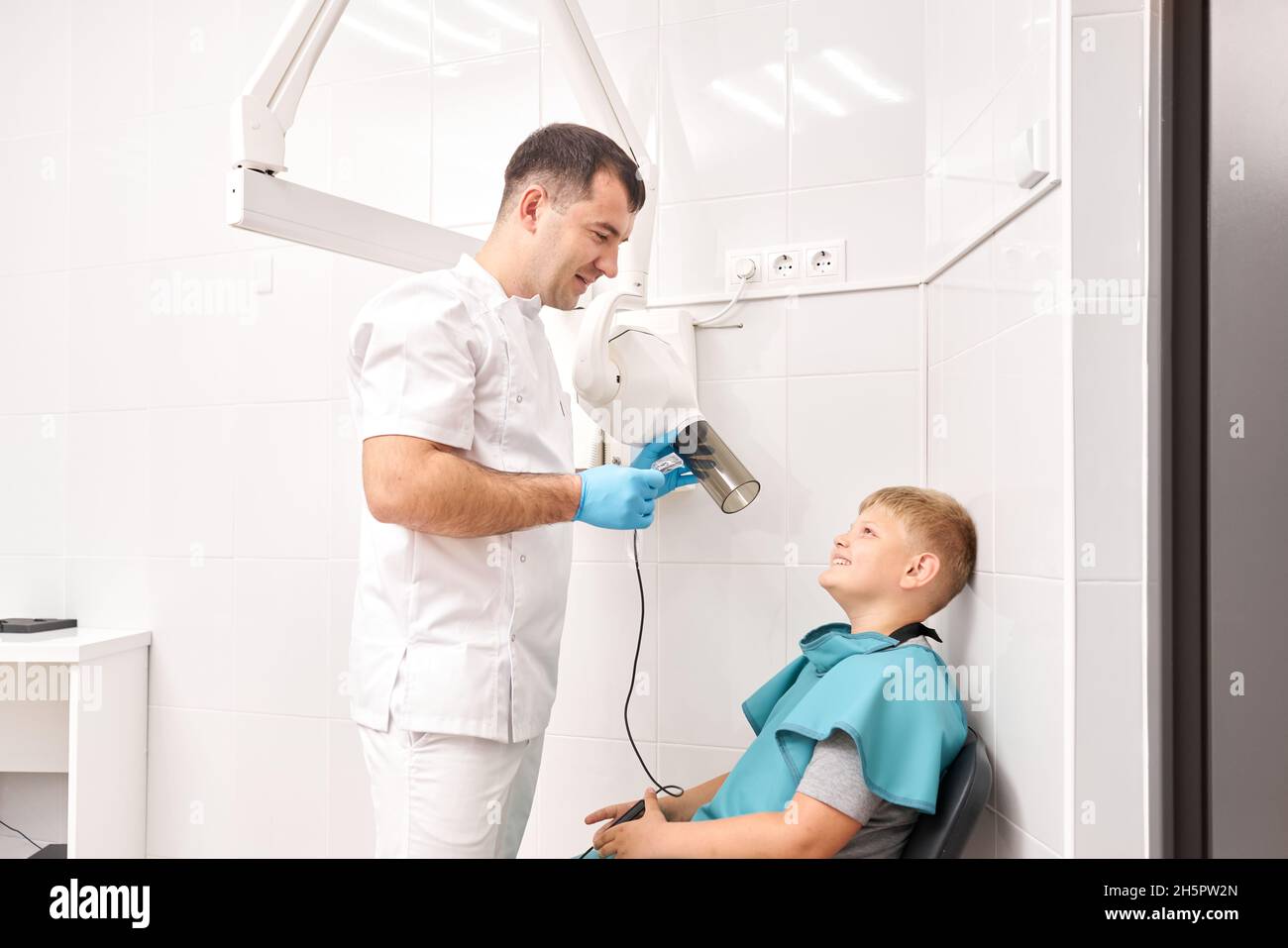 Radiographer taking teeth radiography to a boy using digital xray machine in pediatric dental