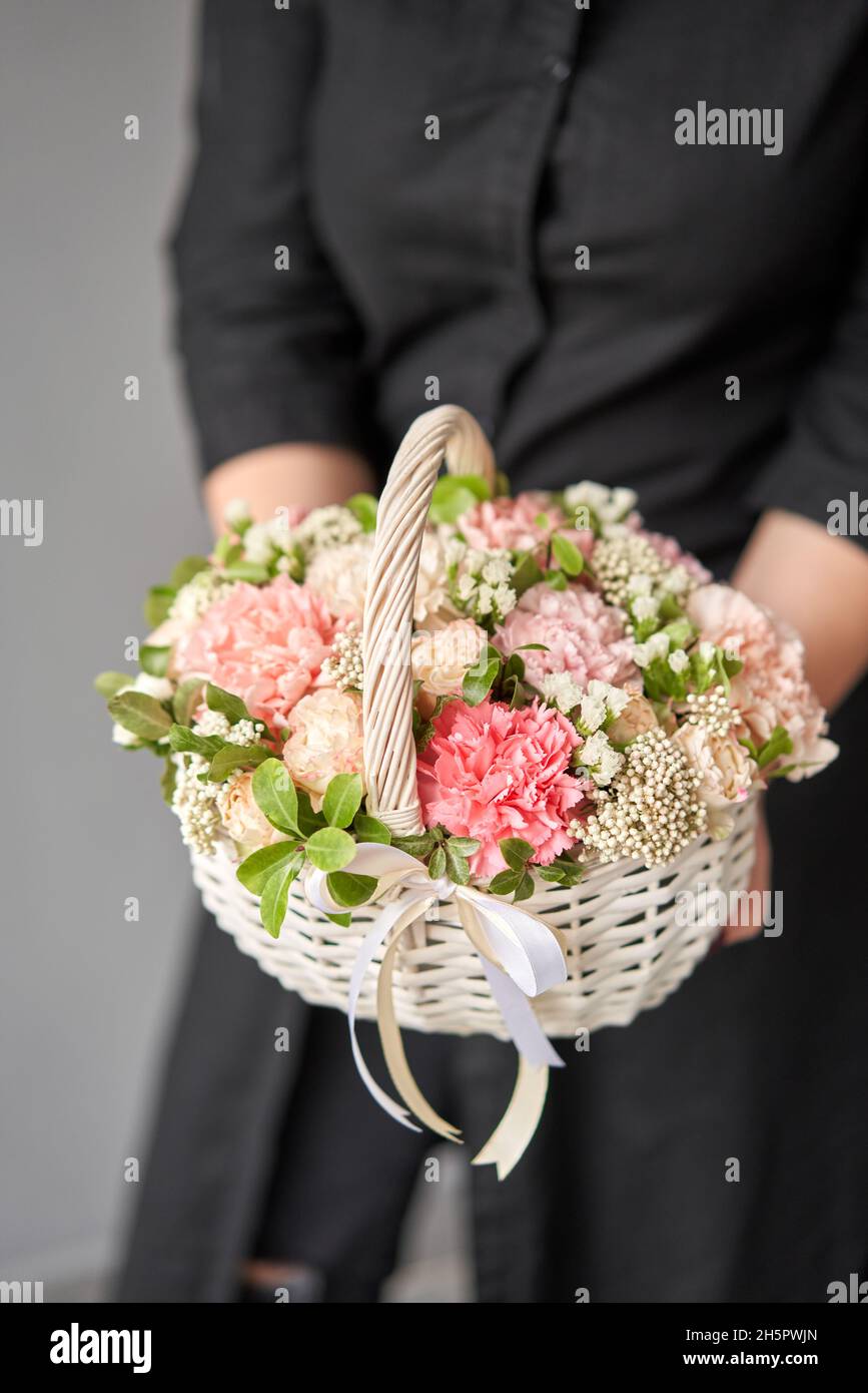 Flower arrangement in Wicker basket. Beautiful bouquet of mixed flowers in woman hand. Handsome fresh bouquet. Small flower shop and Flowers delivery Stock Photo