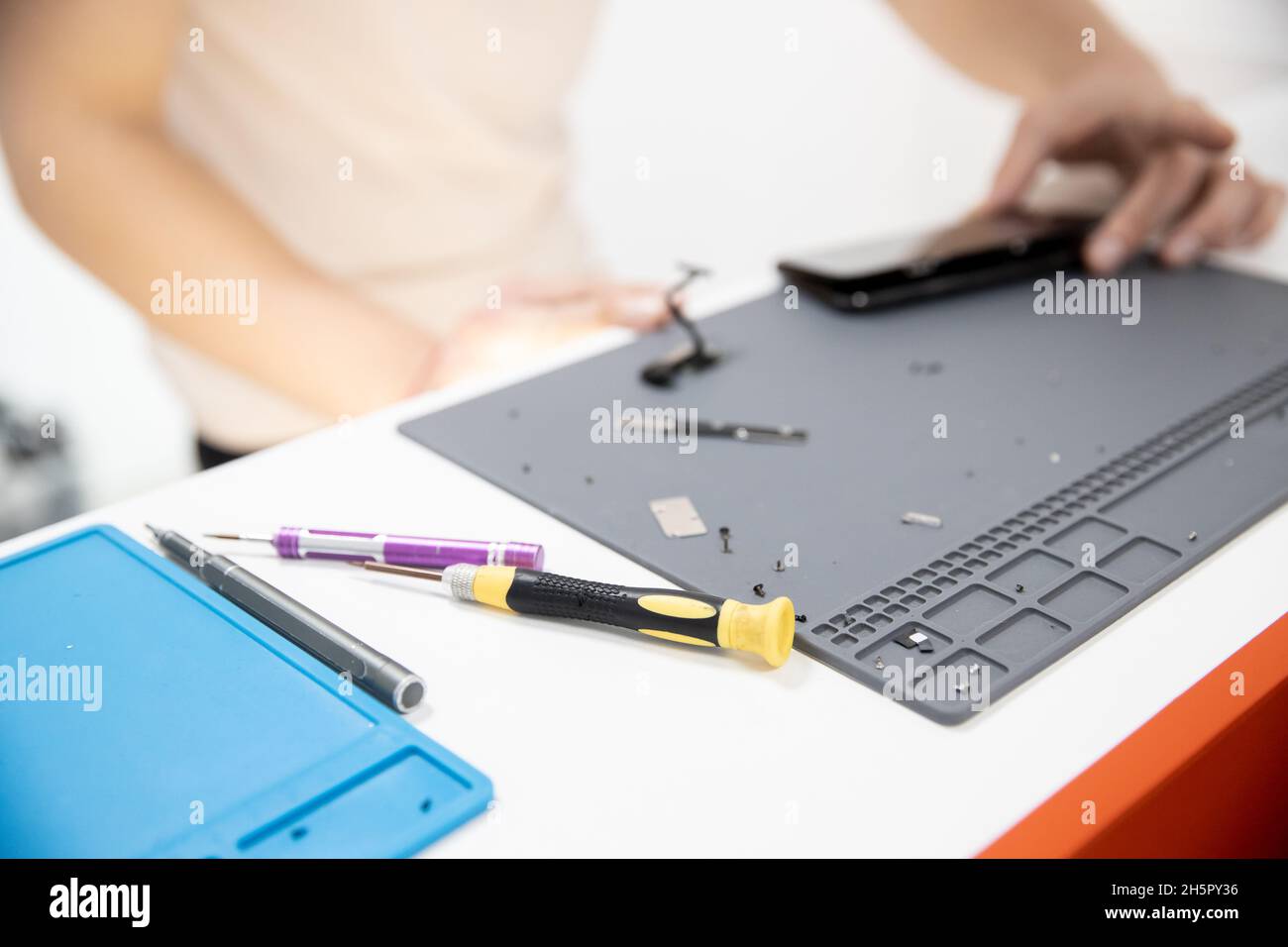 Master disassembles modern mobile phone, repairs and replaces battery, broken screen. Stock Photo