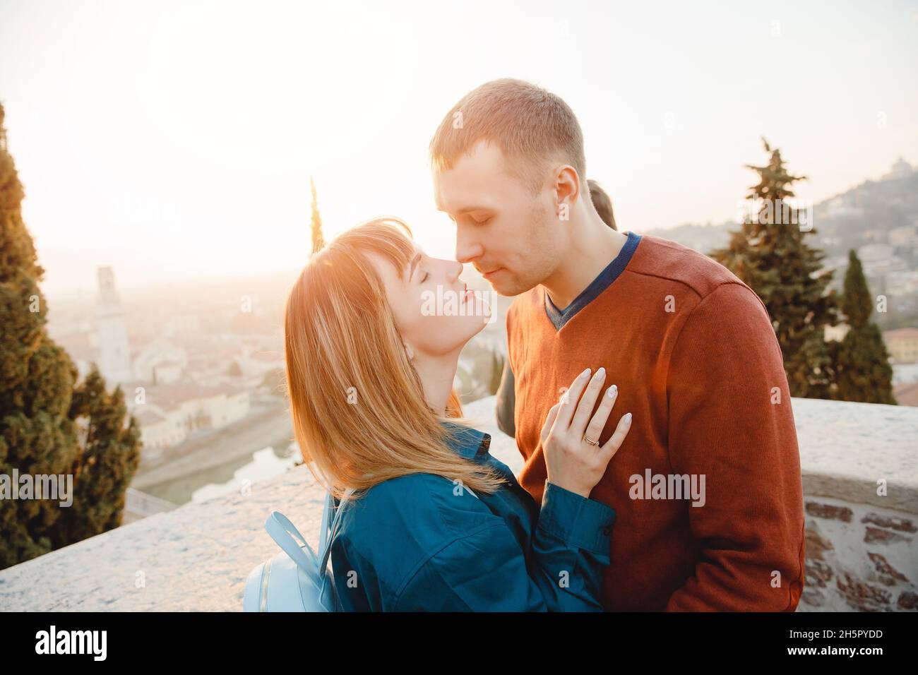 Romantic couple man and girl hug and kiss on sunset background of city Verona Italy. Travel concept. Stock Photo