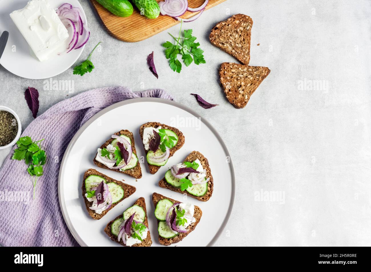 Canapes with toasted bread with sunflower and flax seeds, feta cheese, cucumber and onion Stock Photo