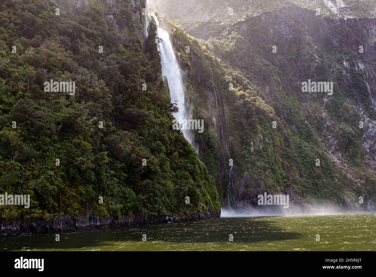 Landscape with a small waterfall and a mountain overgrown with greenery. Fiordland National Park. New Zealand Stock Photo