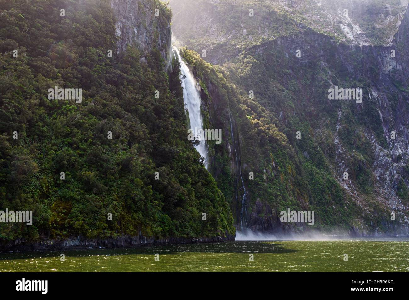 Landscape with a small waterfall and a mountain overgrown with greenery. Fiordland National Park. South Island, New Zealand Stock Photo