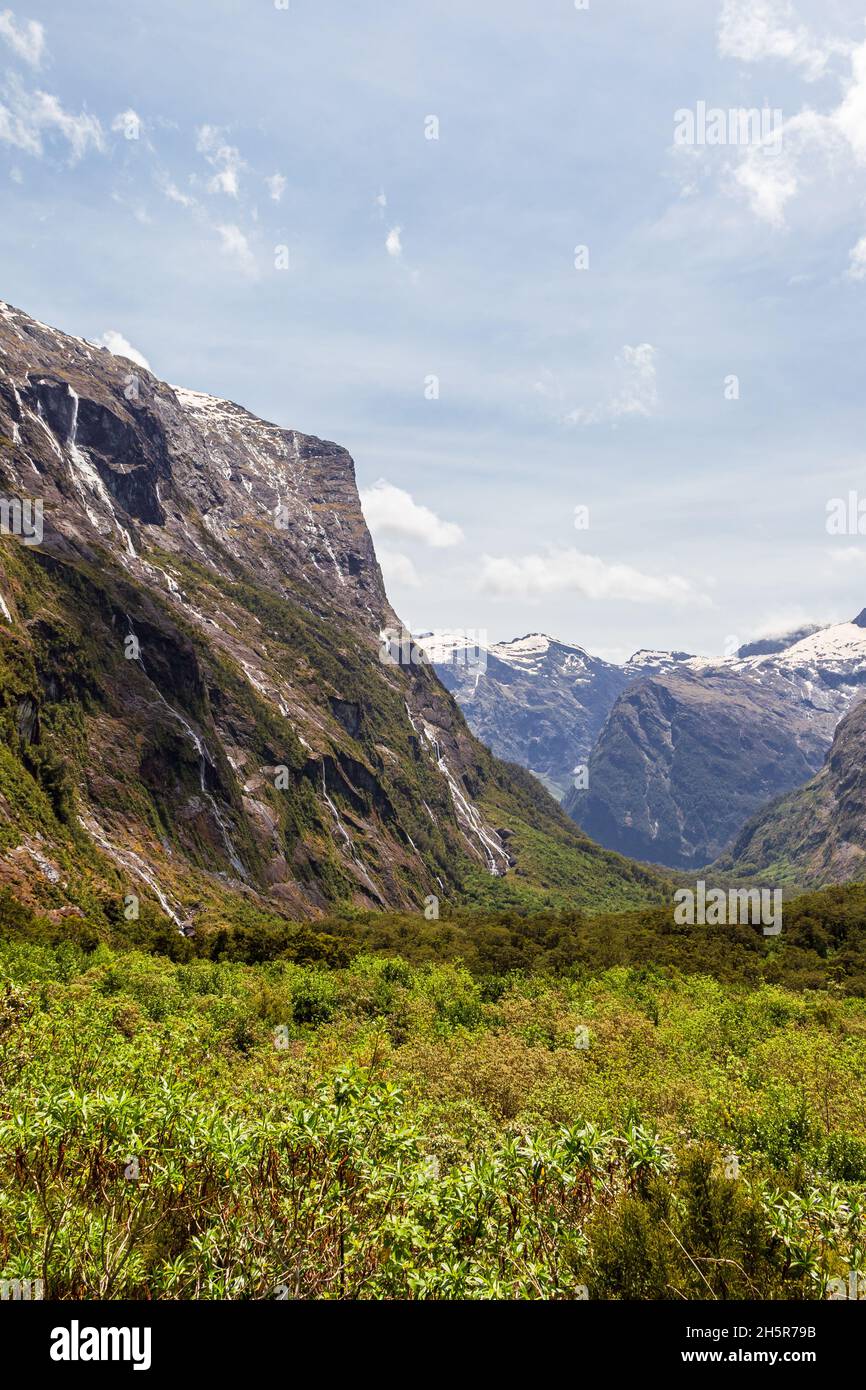 Sheer cliffs and green valley on the way to Fiordland. South Island, New Zealand Stock Photo