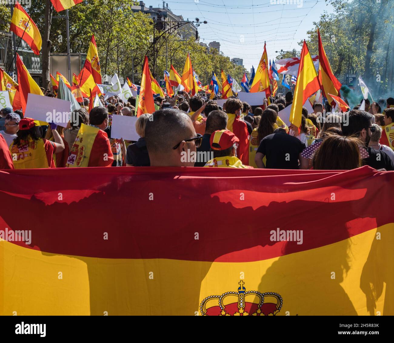 October 12th, 2021, Spain's National Day, better known as Hispanic Day: rear view of a man walking through the crowd and holding the Spanish flag. Stock Photo
