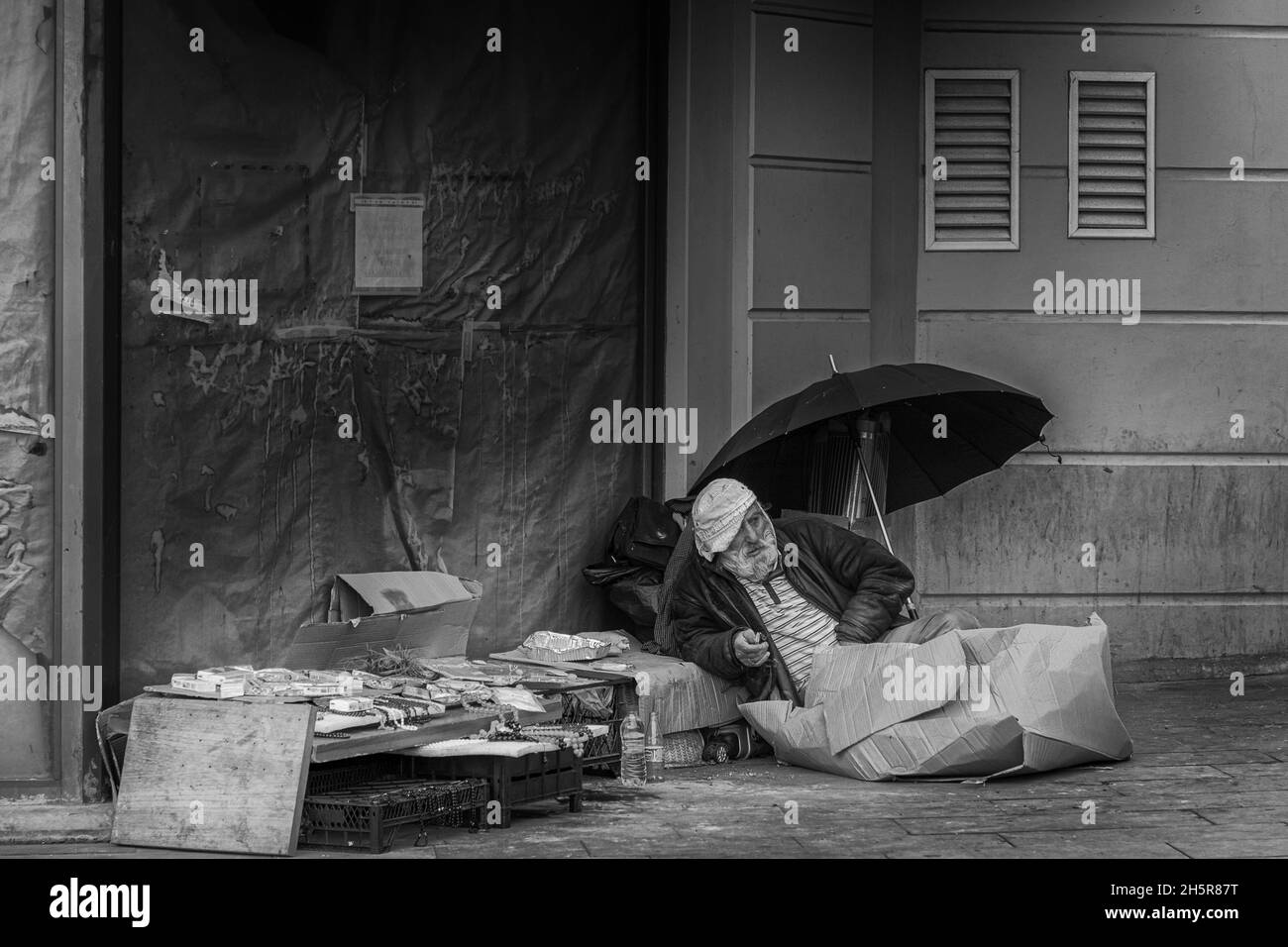 Istanbul, Turkey-Nov.9, 2021:Homeless man sitting on the street, near the wall and cart with his stuff near Sirkeci train Station in Istanbul.Number o Stock Photo