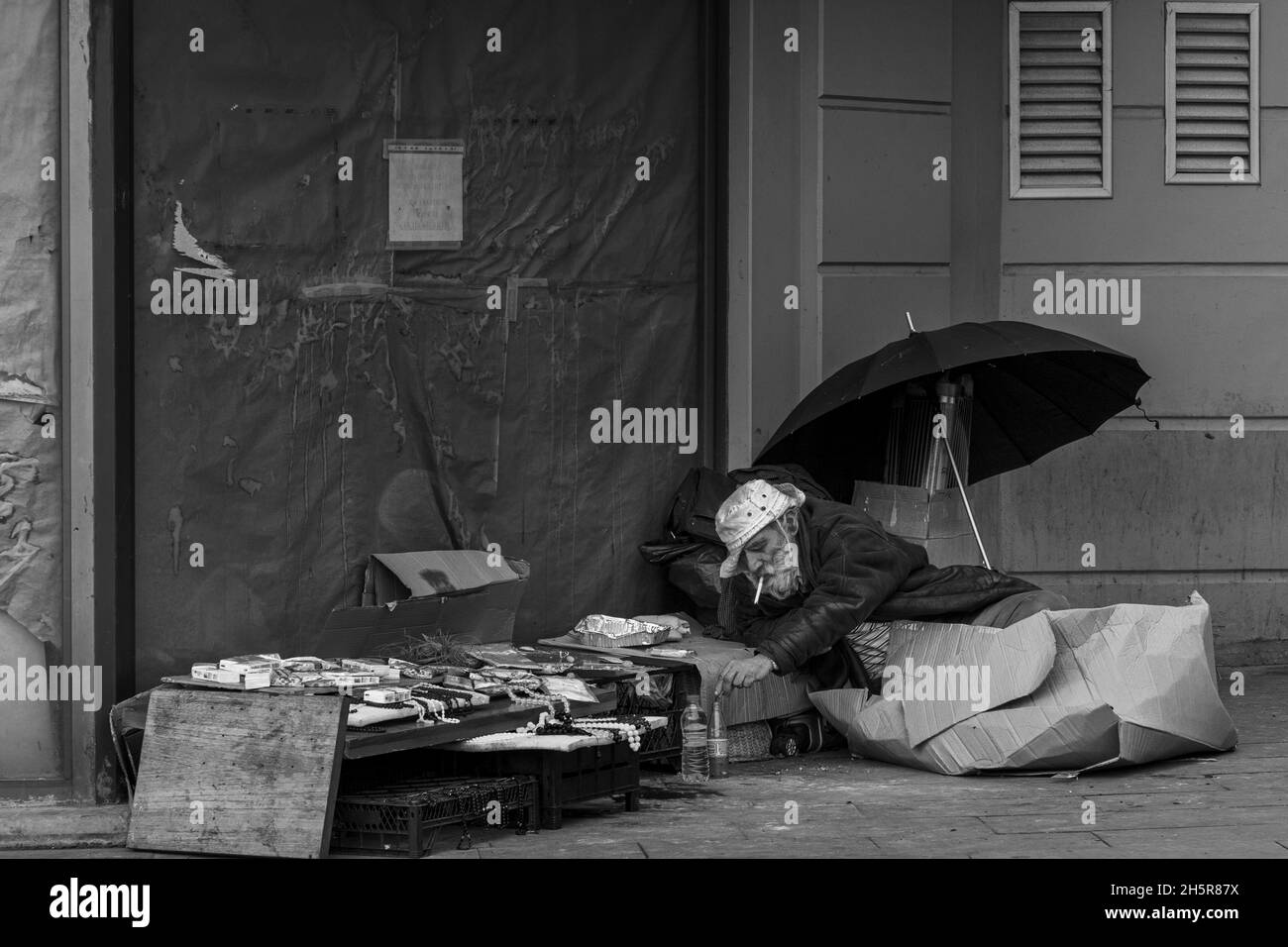 Istanbul, Turkey-Nov.9, 2021:Homeless man sitting on the street, near the wall and cart with his stuff near Sirkeci train Station in Istanbul.Number o Stock Photo