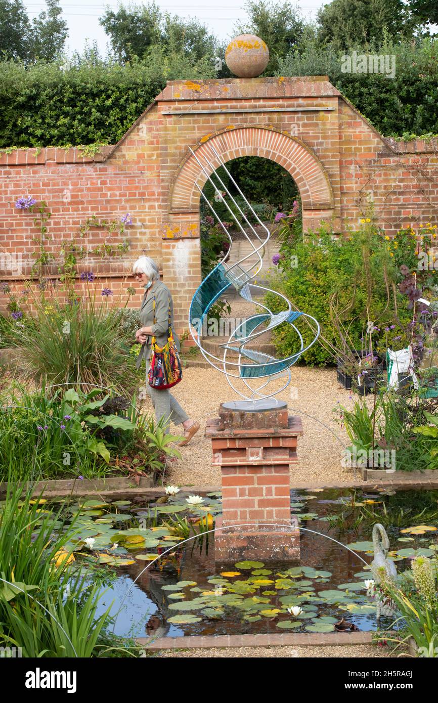 East Ruston Old Vicarage Gardens. Decorative, imaginative, modern sculpture, lily pond, aquatic, terrestrial, living plants, backdrop of considered br Stock Photo