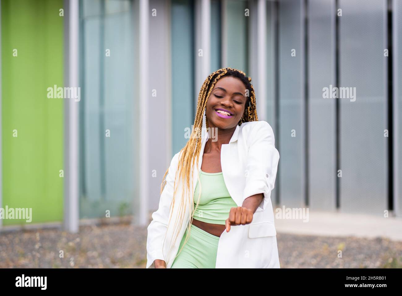 Portrait of a smiling african woman with braids dancing energically in ...