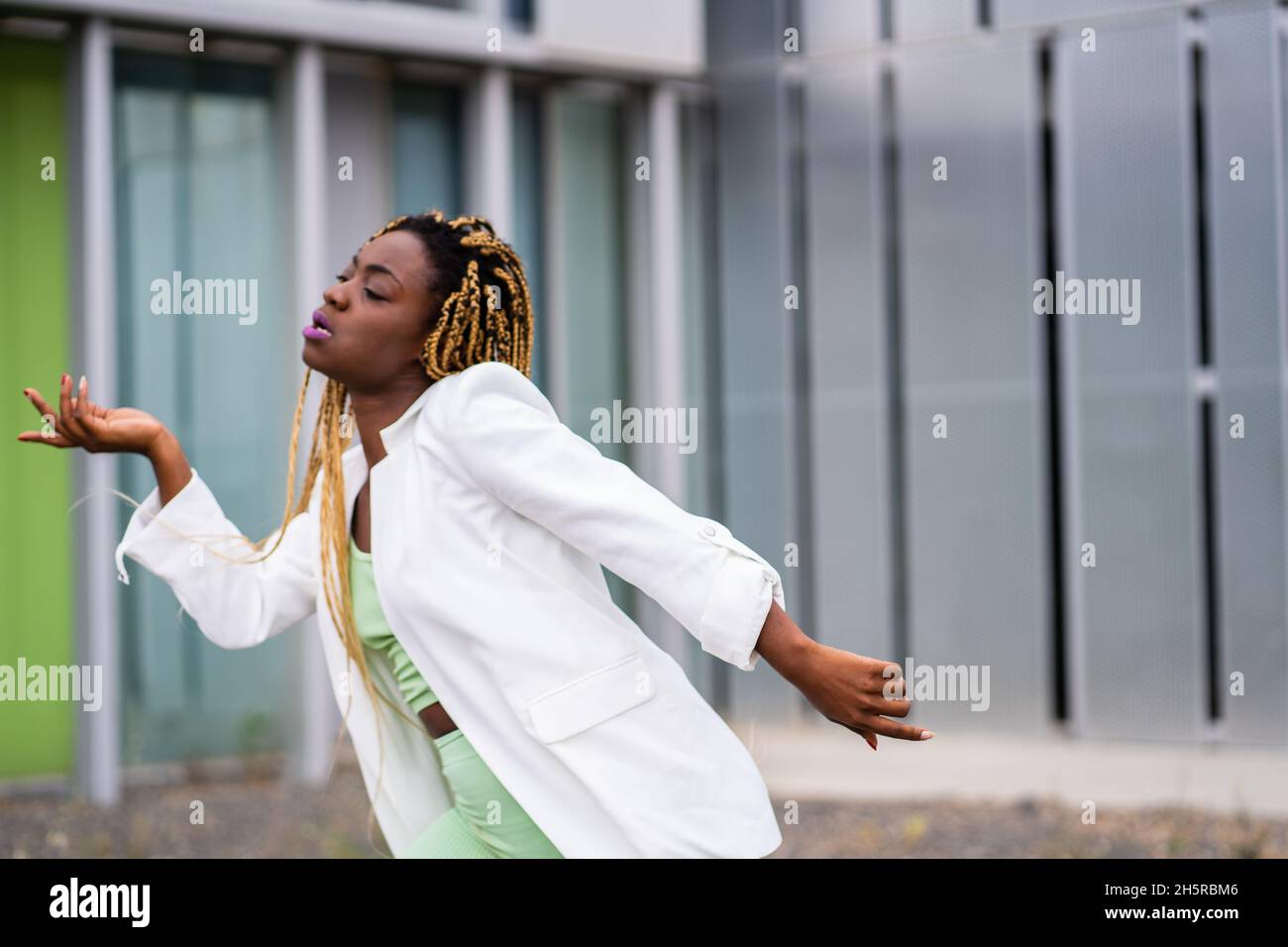 Portrait of a black woman with braids dancing concentrated in front of ...