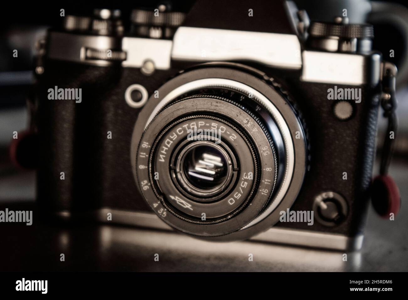 Detail of a vintage old 50mm USSR lens on a silver and black hybrid camera body on a grey desk top Stock Photo