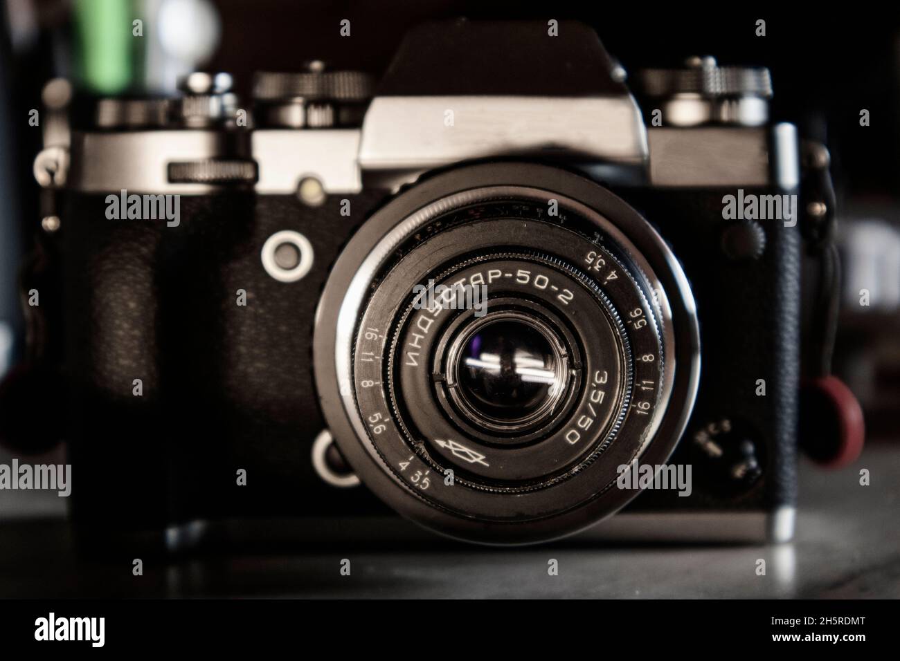 Detail of a retro vintage old 50mm USSR lens on a silver and black hybrid camera body on a grey desk top Stock Photo