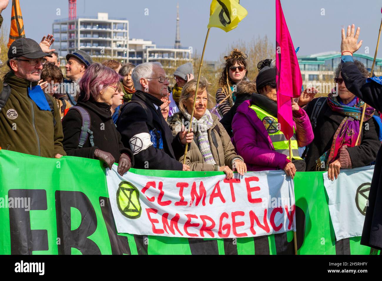 Street photograph of a diverse group of climate change demonstrators holding a large green banner with flags and placards.  Range of age groups. Stock Photo