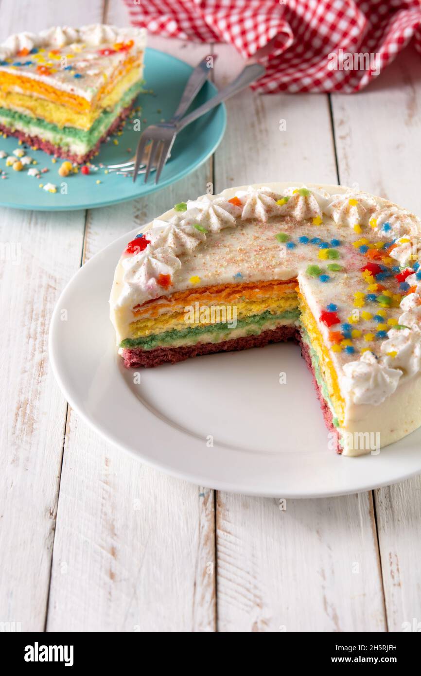 Rainbow layer cake on white wooden table Stock Photo