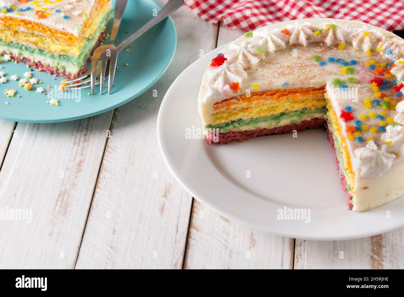 Rainbow layer cake on white wooden table Stock Photo