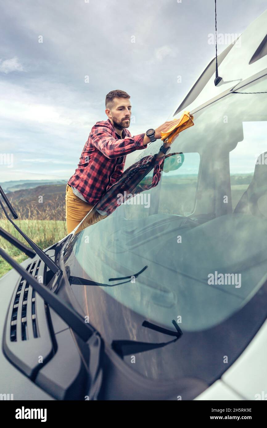 Man cleaning camper van windshield outdoor Stock Photo