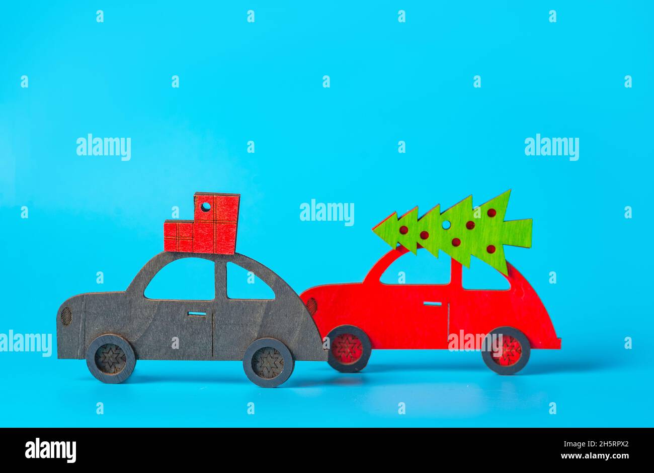 New year, christmas concept. Festive shopping. Several cars with Christmas decorations, Christmas trees on the roof on a blue background. Christmas ba Stock Photo