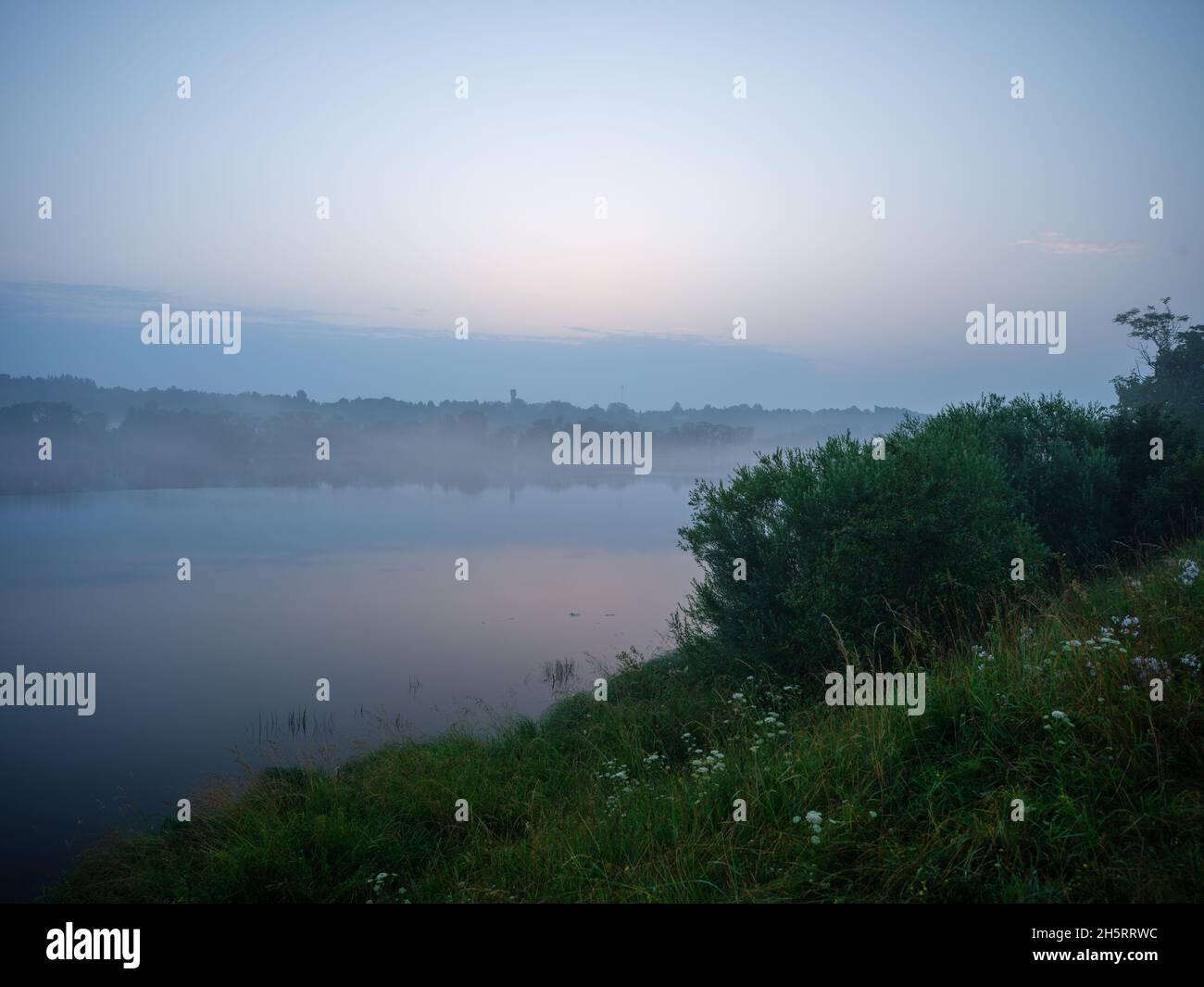 misty morning by the lake with calm water, fog and reflections of trees ...