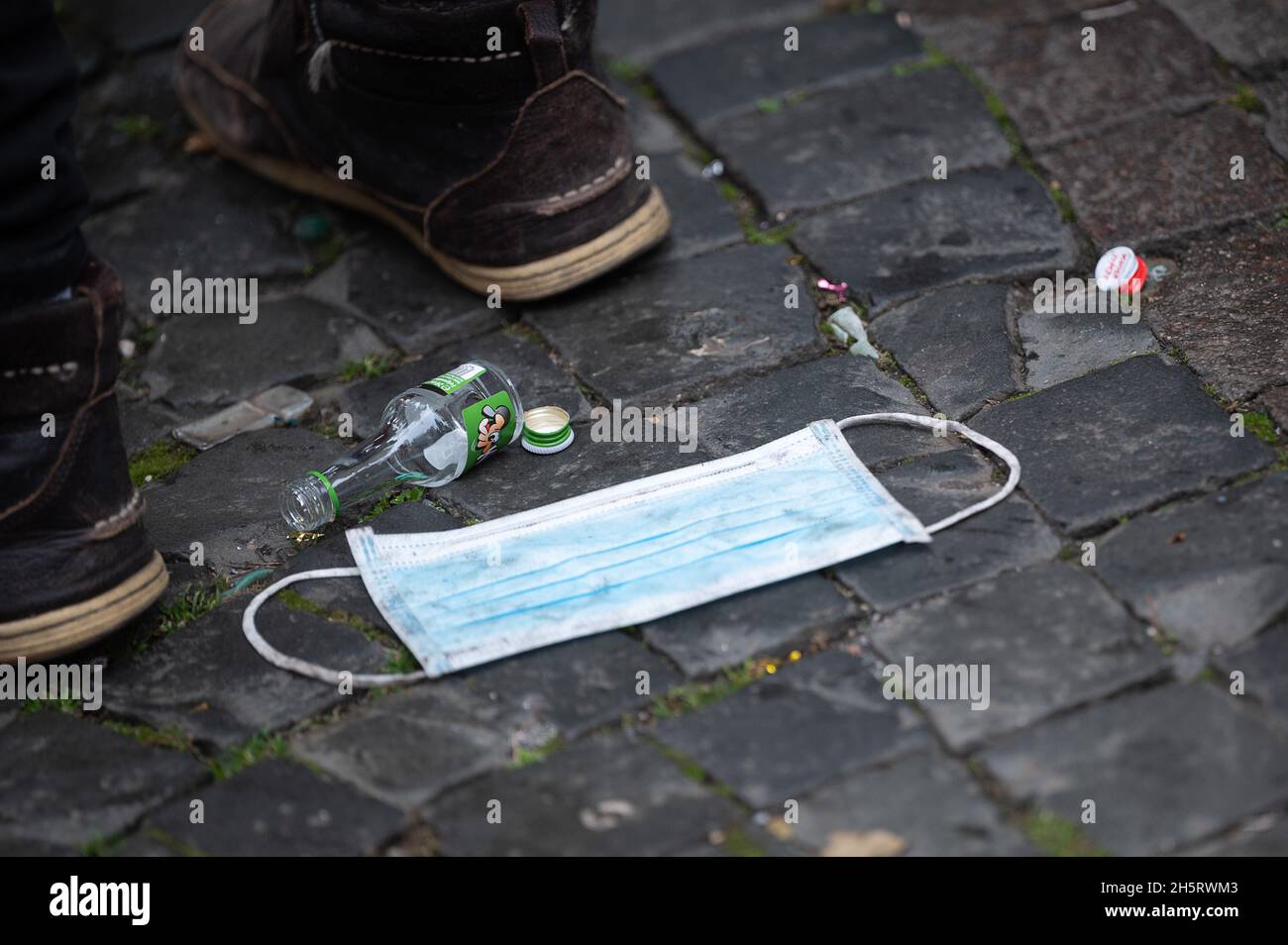 Mainz, Germany. 11th Nov, 2021. A mask and an empty bottle lie on Schillerplatz after the reading of the foolish basic law. Only those who have bought a ticket in advance are allowed to join the party. The 2G rule applies on Schillerplatz. Credit: Sebastian Gollnow/dpa/Alamy Live News Stock Photo