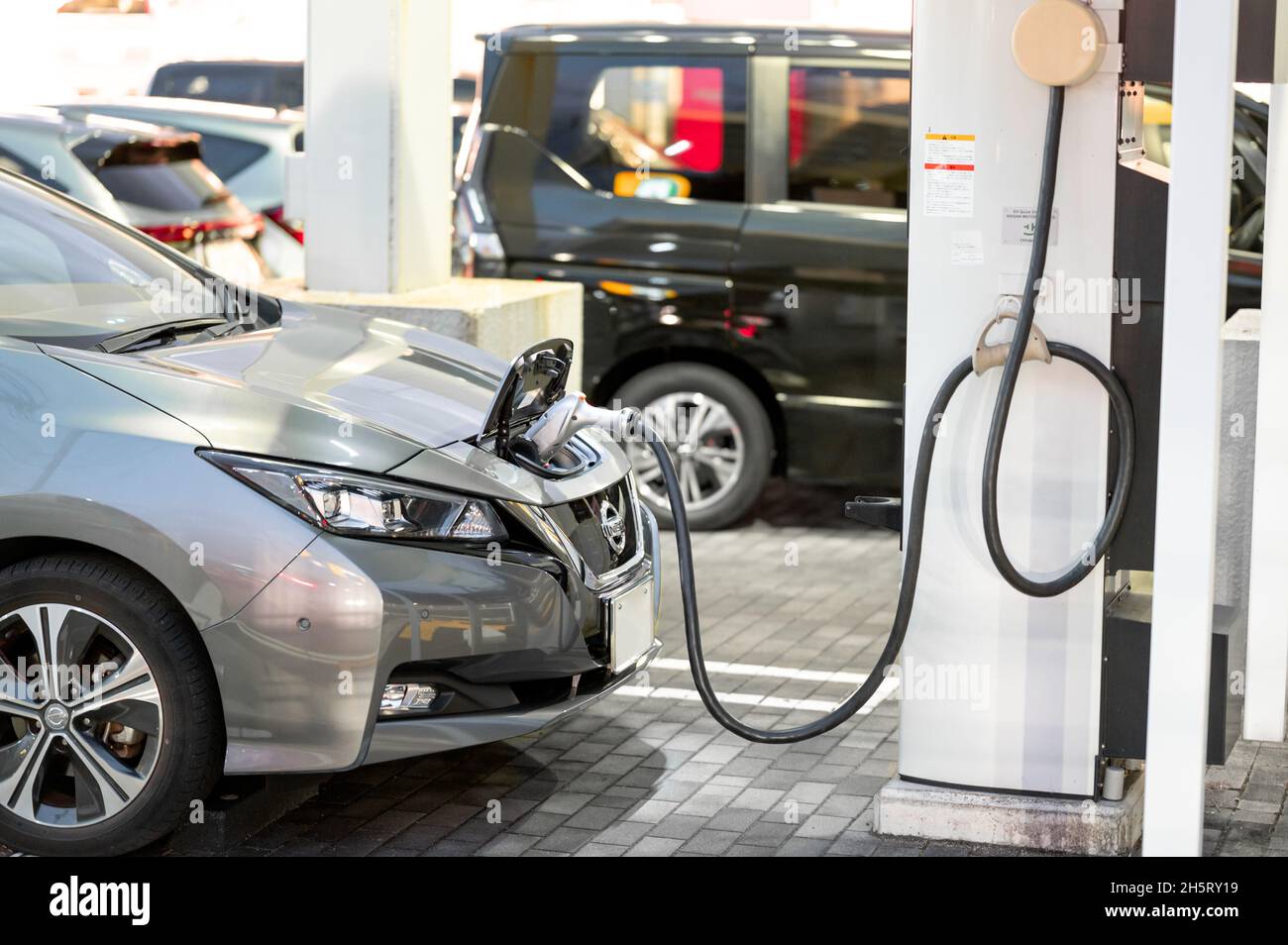 Nissan Leaf being charged at the EV Quick charging point for electric vehicles. Electric car being charged by a cable. Stock Photo