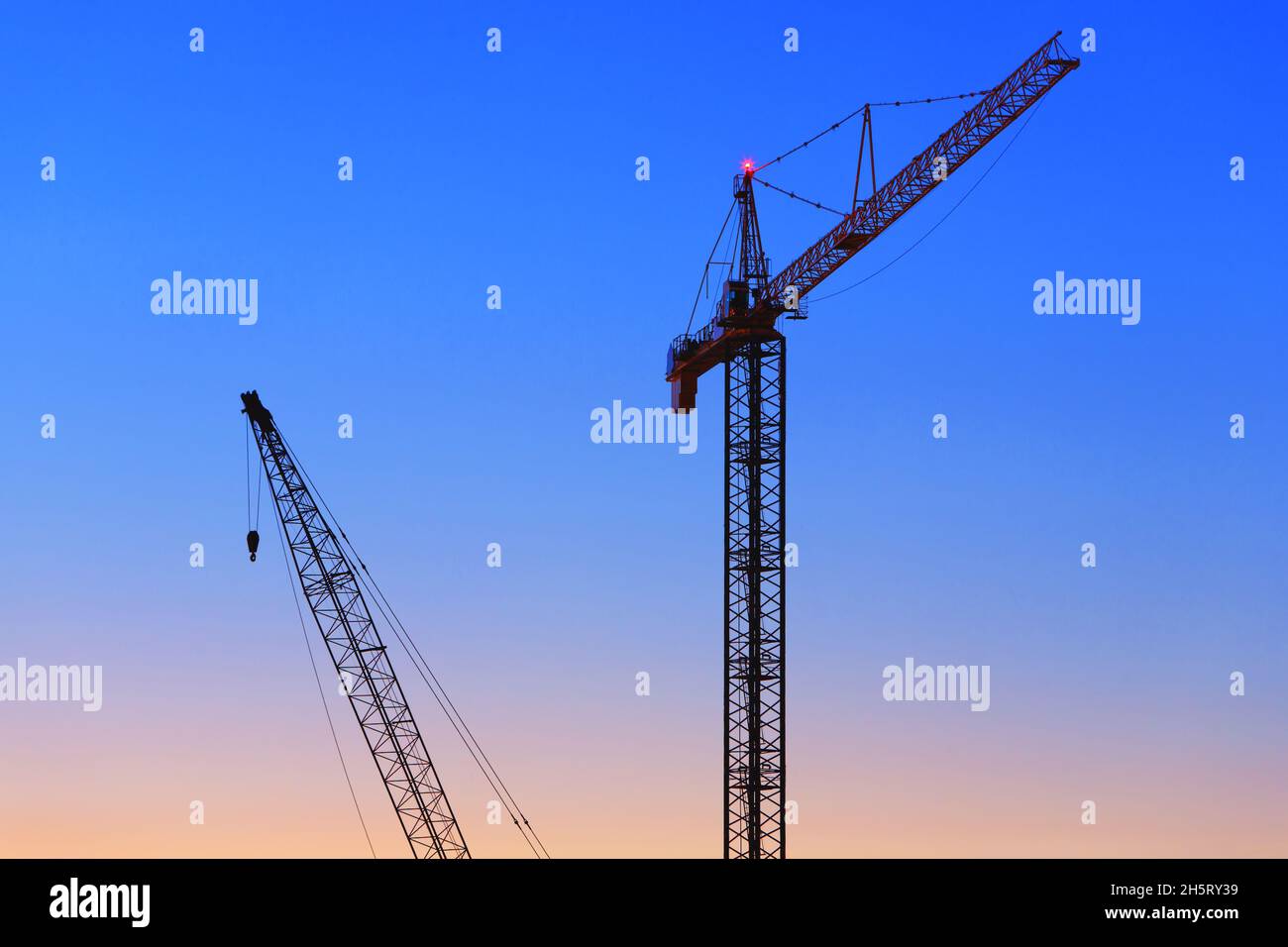 Construction cranes against the sunset sky Stock Photo - Alamy