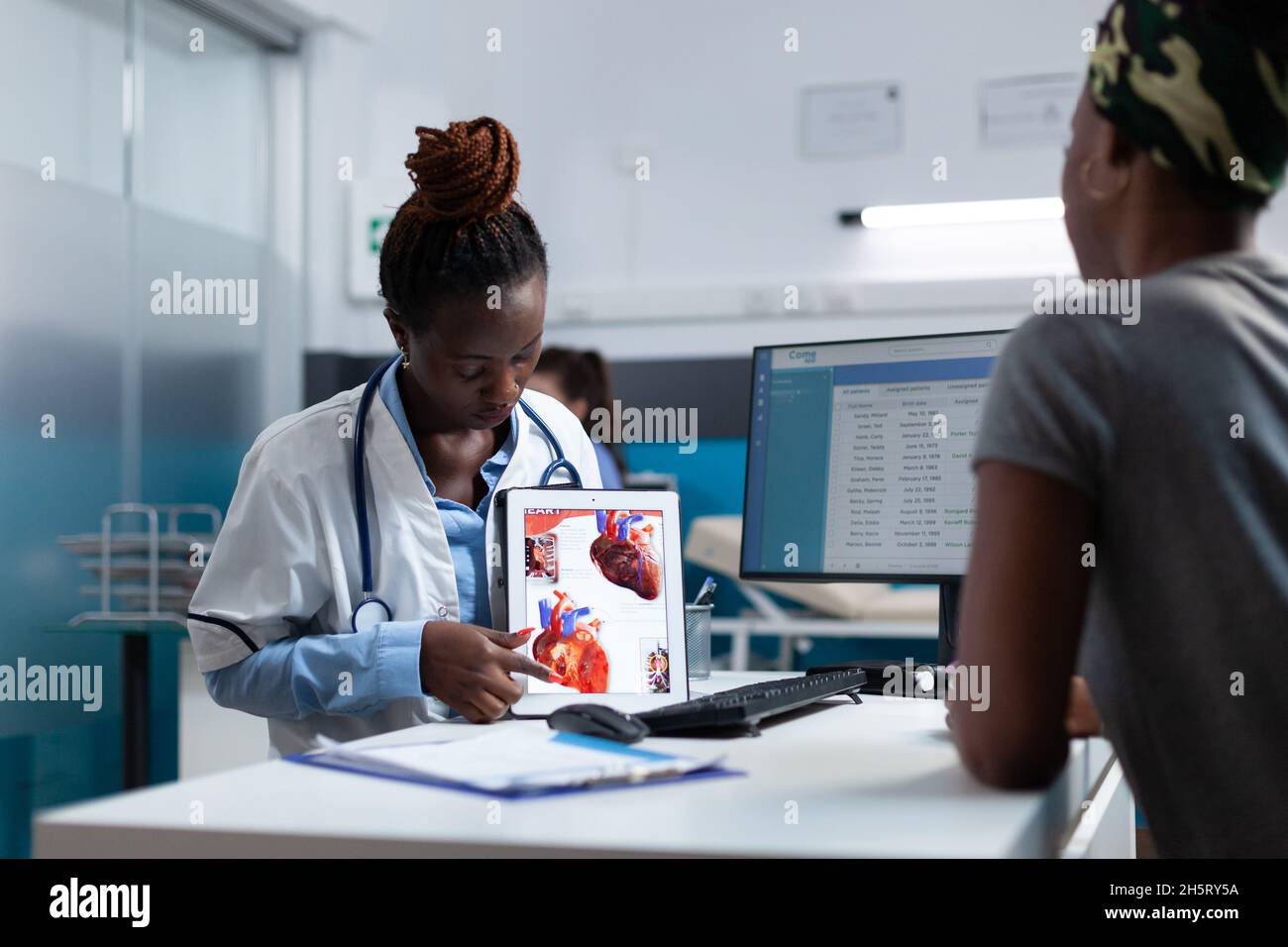 African american specialist cardiologist explaining heart radiography expertise to sick patient discussing medication treatment during clinical appointment. Doctor woman working in hospital office Stock Photo