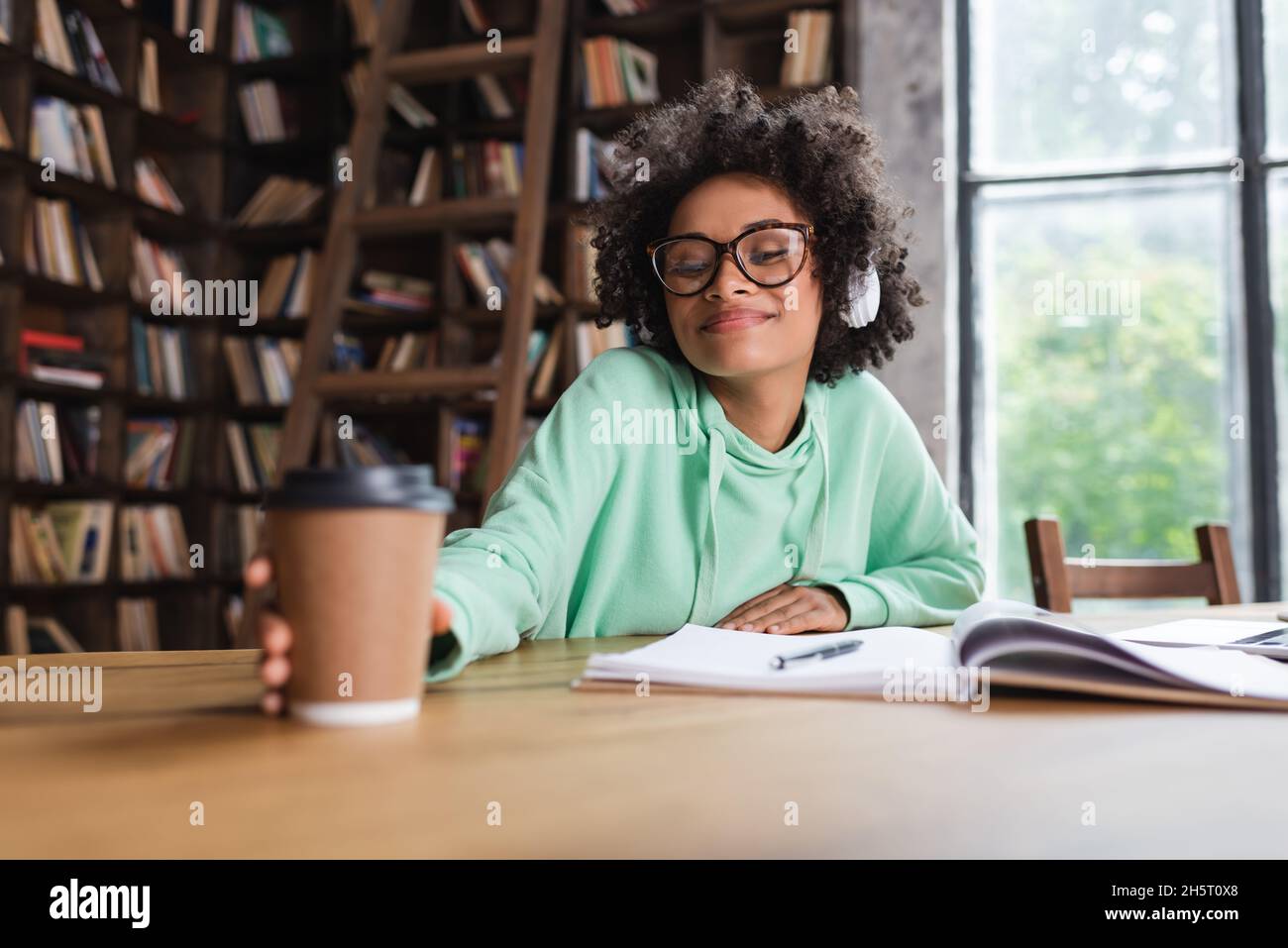 happy african american student in eyeglasses and headphones reaching ...