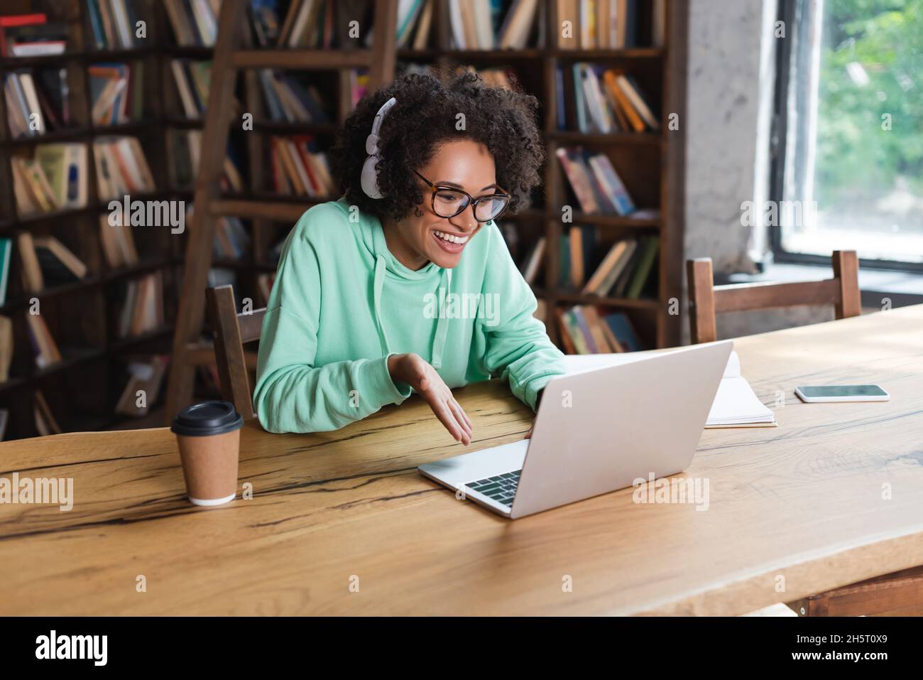 happy african american student in eyeglasses and headphones using ...
