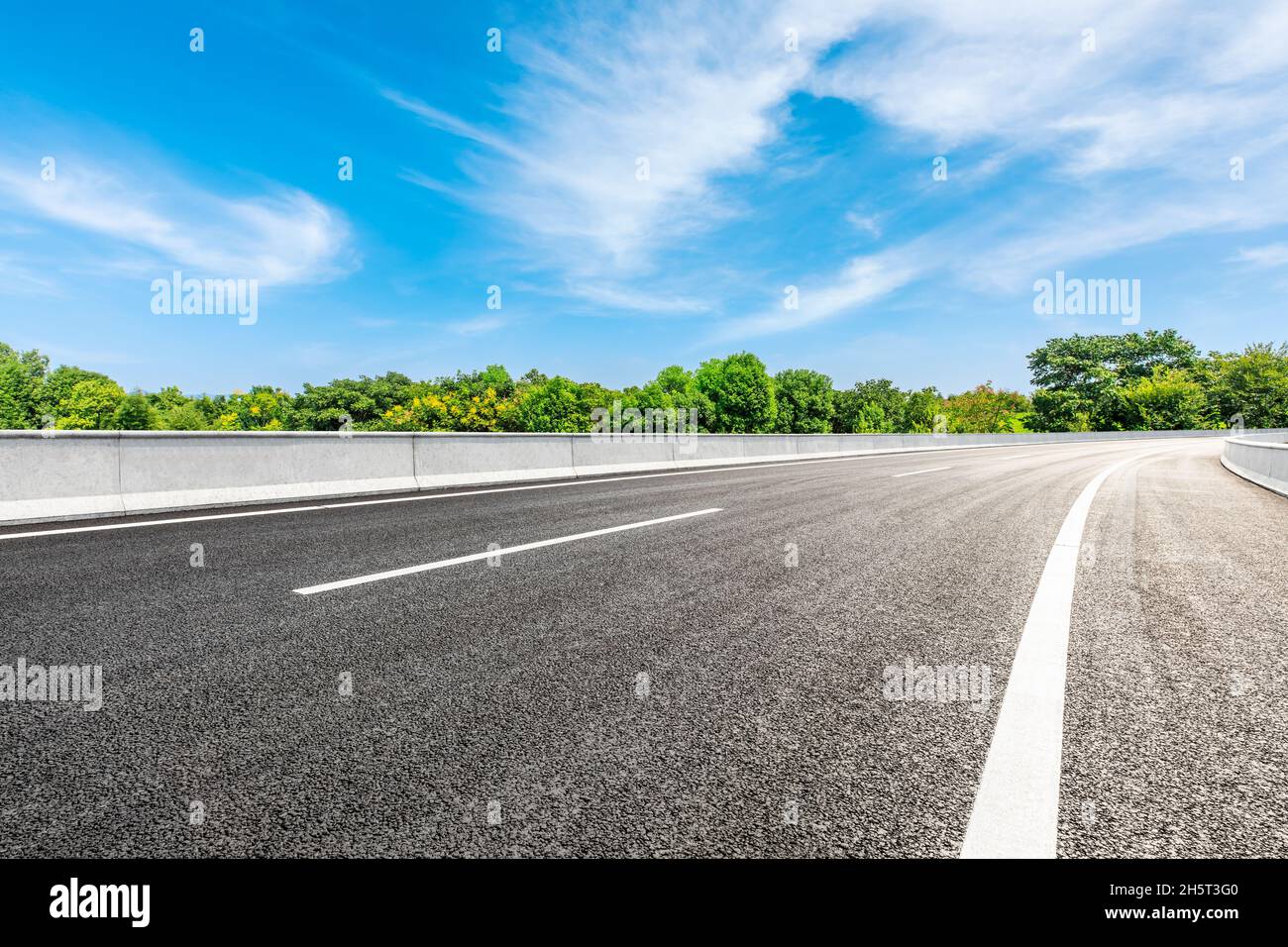 Asphalt road and green forest under blue sky Stock Photo - Alamy