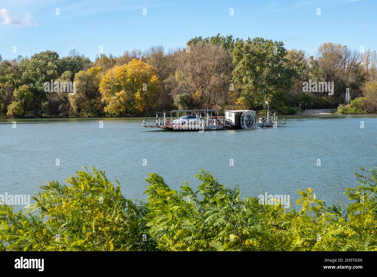 Ferry transporing cars and passengers across river Tiszaon asunny autumn day,  Tiszacsege, Hungary, Hungary Stock Photo