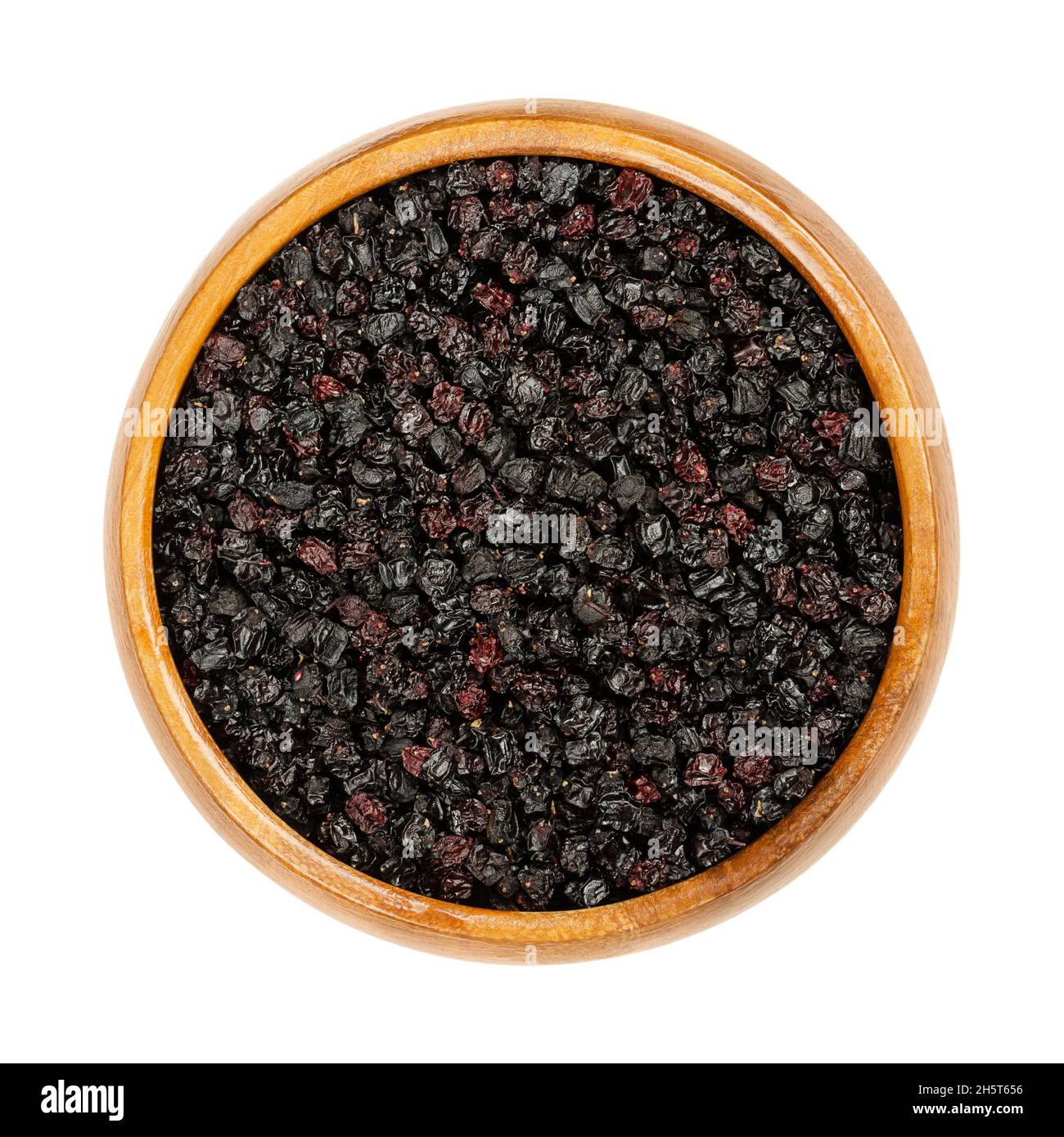 Dried elderberries in a wooden bowl. Ripe Sambucus berries. Elder or elderberry. Raw berries are not edible, but are used for steeping in hot teas. Stock Photo