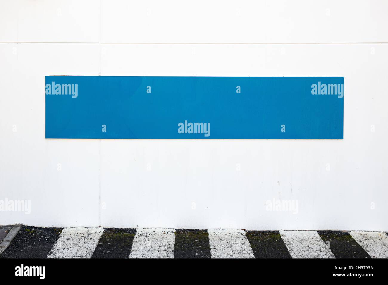 Blank blue sign placed on white wall on the outside of building ...