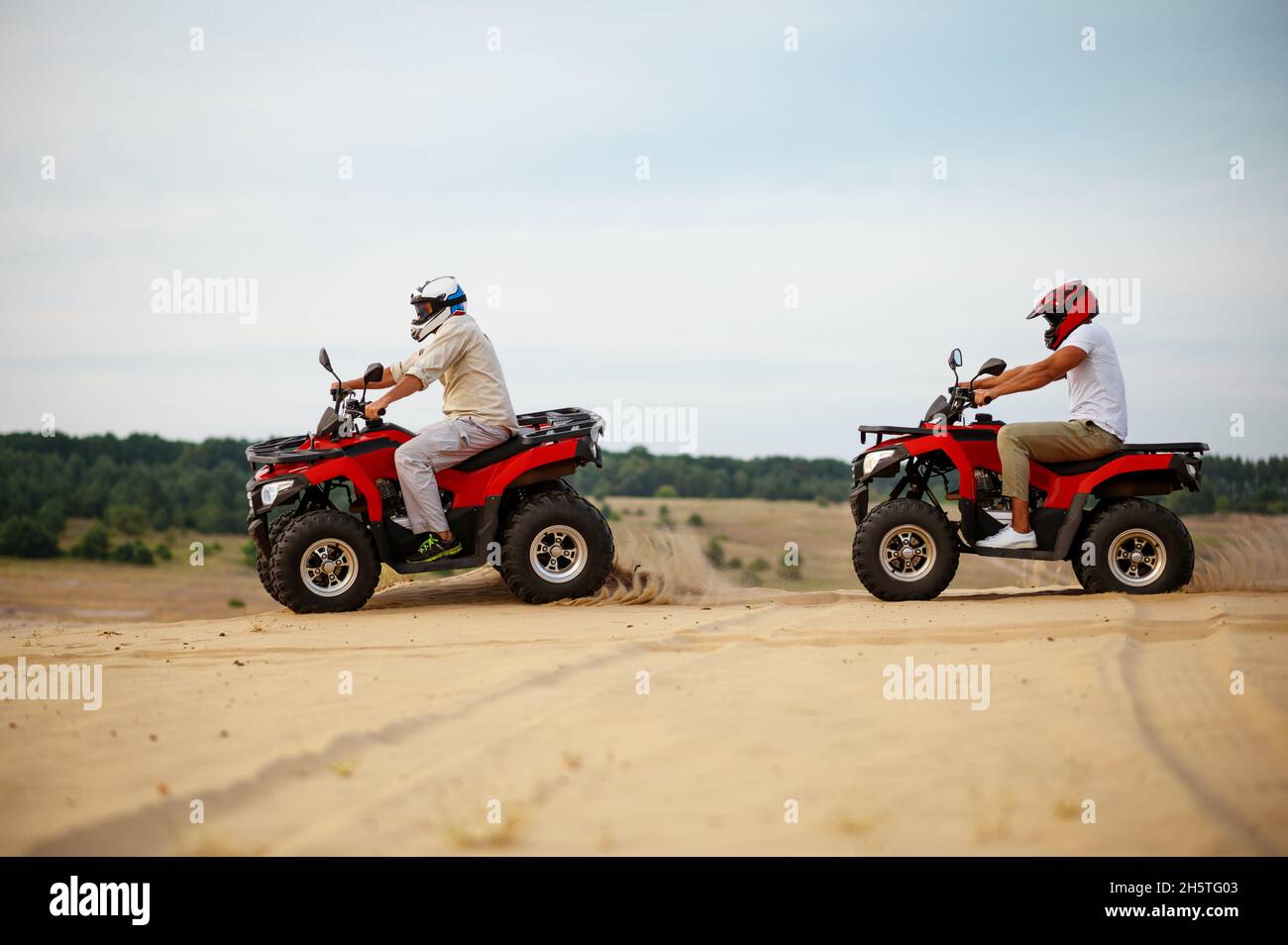 Two men in helmets, atv riding in desert sands Stock Photo - Alamy