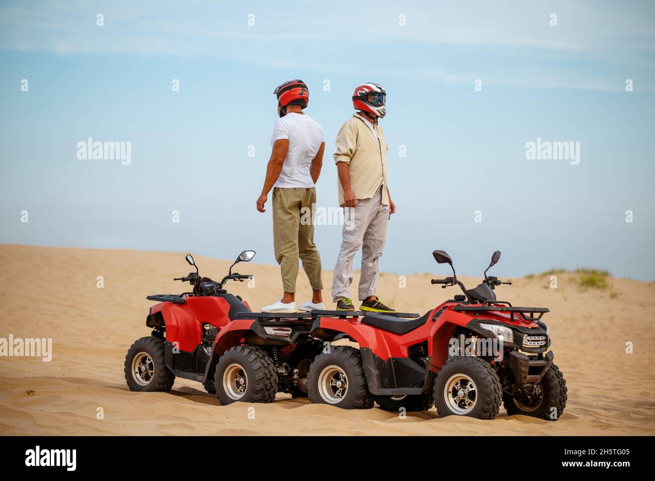 Two racers in helmets stand back to back on atvs Stock Photo