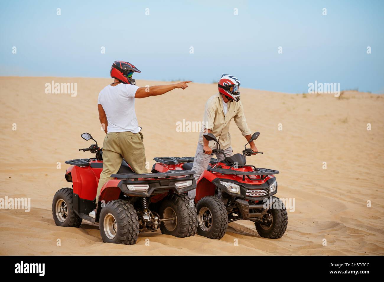 Two men in helmets, atv riding in desert sands Stock Photo Alamy